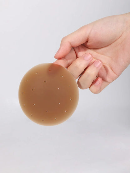 Hand holding a brown adhesive patch against a light gray background