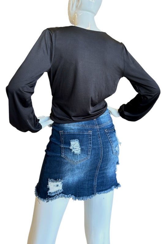 A mannequin wearing a black long-sleeve top and a distressed blue denim mini skirt with frayed hems, shown from the back against a white background.