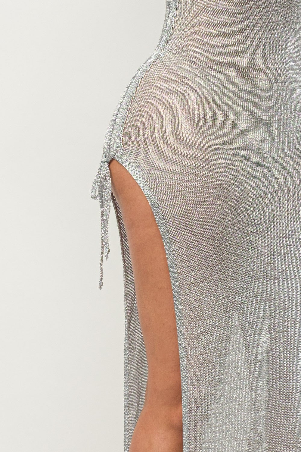 Close-up of a textured silver dress with a side slit on a light gray background