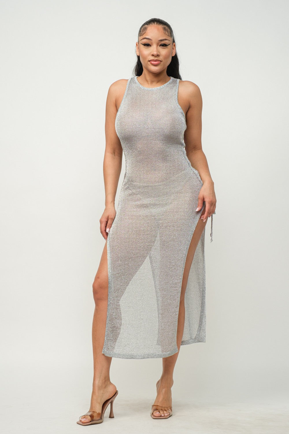Woman wearing a silver mesh dress with a slit on a white background