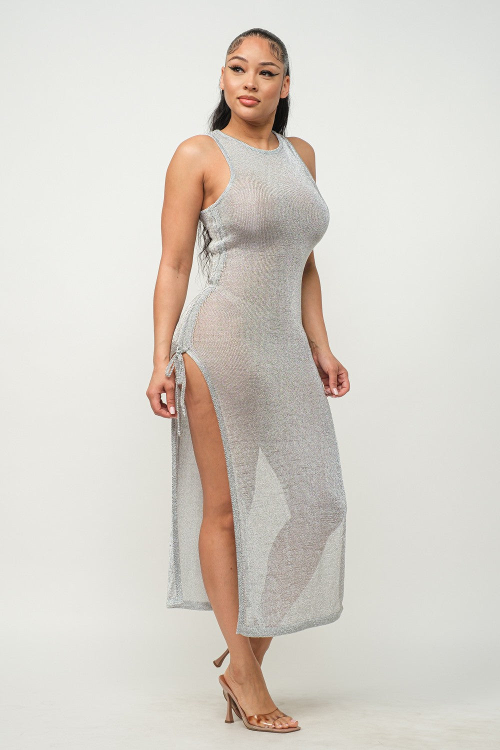 Woman wearing a silver halter neck dress with a slit on a white background