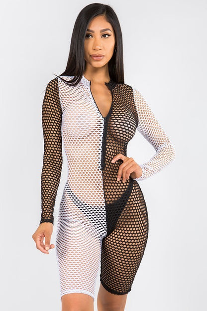 A woman modeling a long-sleeve, bodycon fishnet romper with a split black and white design on a light gray studio background.