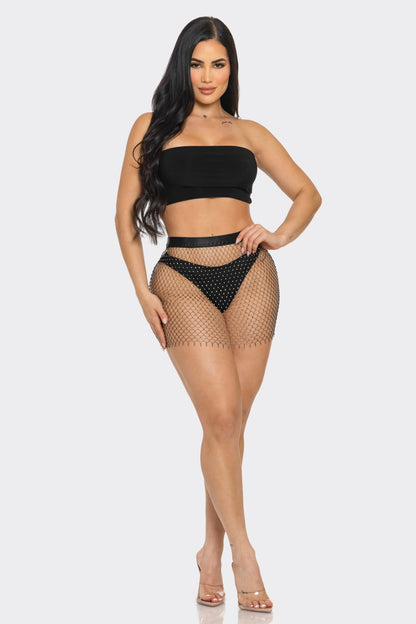 Woman wearing a black strapless top and fishnet skirt on a white background