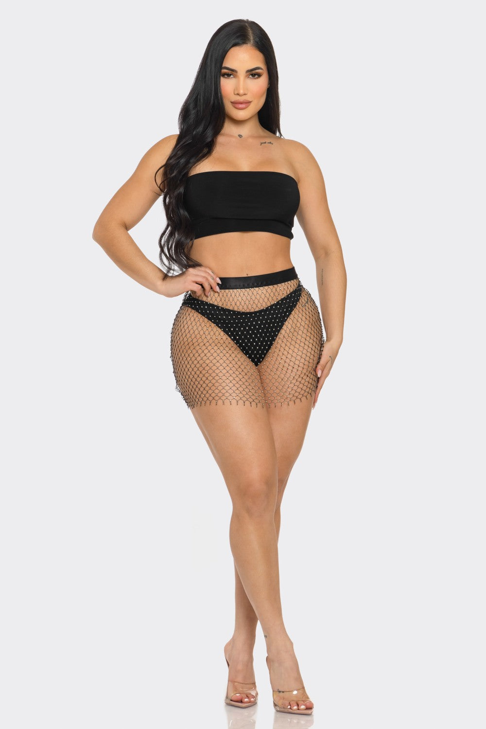 Woman wearing a black strapless top and fishnet skirt on a white background