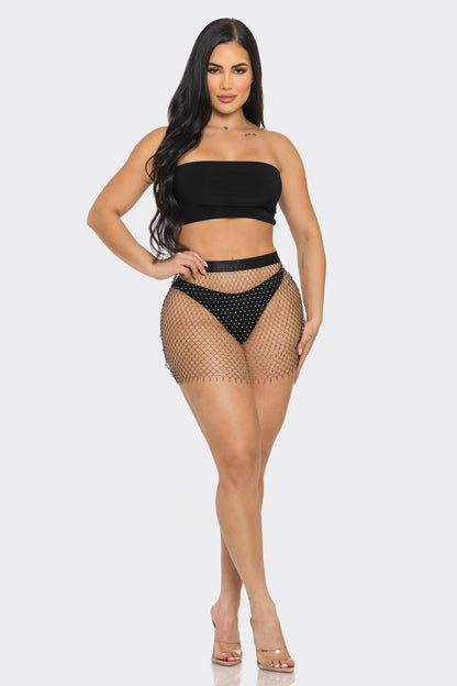Woman wearing a black strapless top and fishnet skirt on a white background