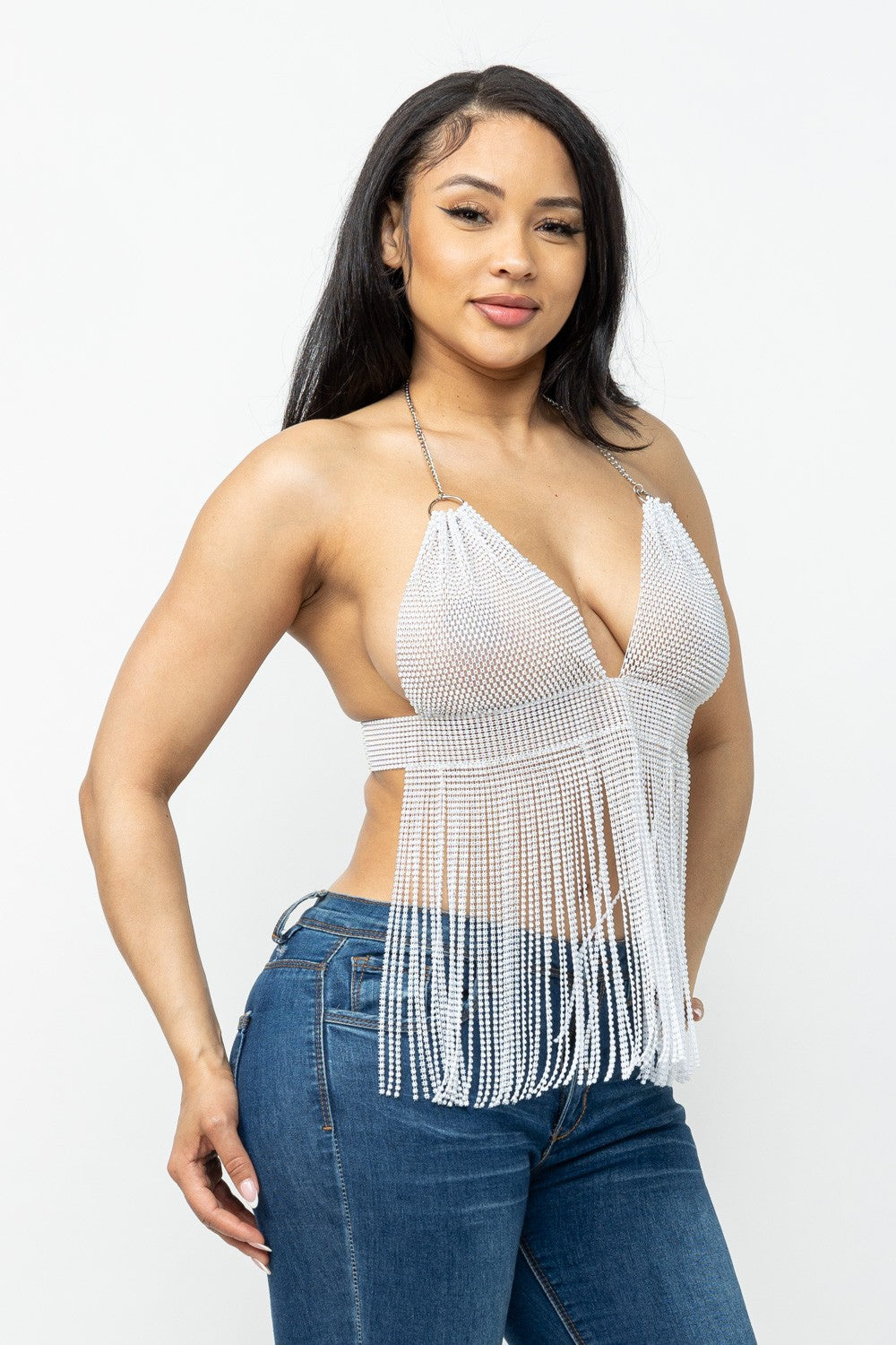 Woman wearing a white fringe top and blue jeans on a white background