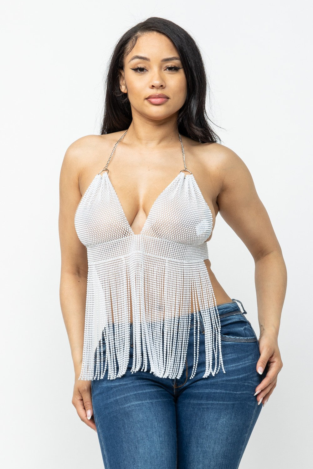 Woman wearing a white fringe top and blue jeans on a white background