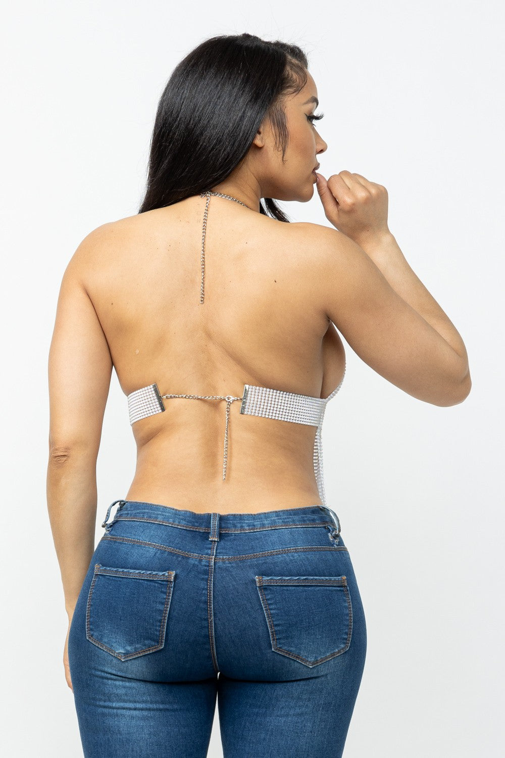 Woman wearing a strappy top and blue jeans on a white background