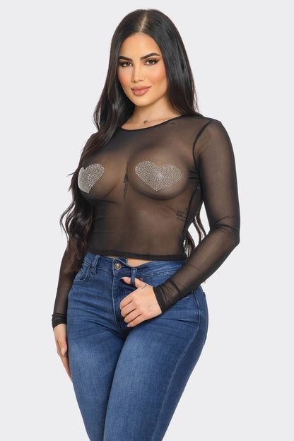 Woman wearing a sheer black top and blue jeans on a white background