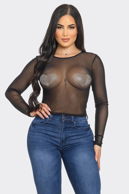 Woman wearing a sheer black top with cut-out design and blue jeans on a white background