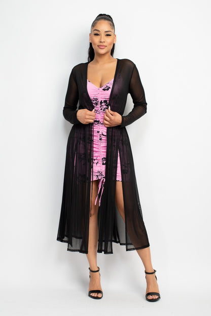 Woman wearing a pink dress with a black sheer cover-up on a white background