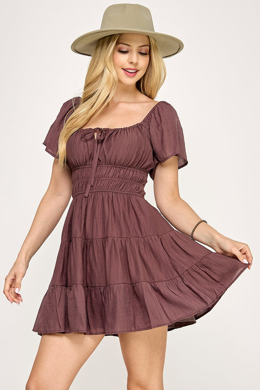 Woman wearing a brown dress and beige hat on a white background