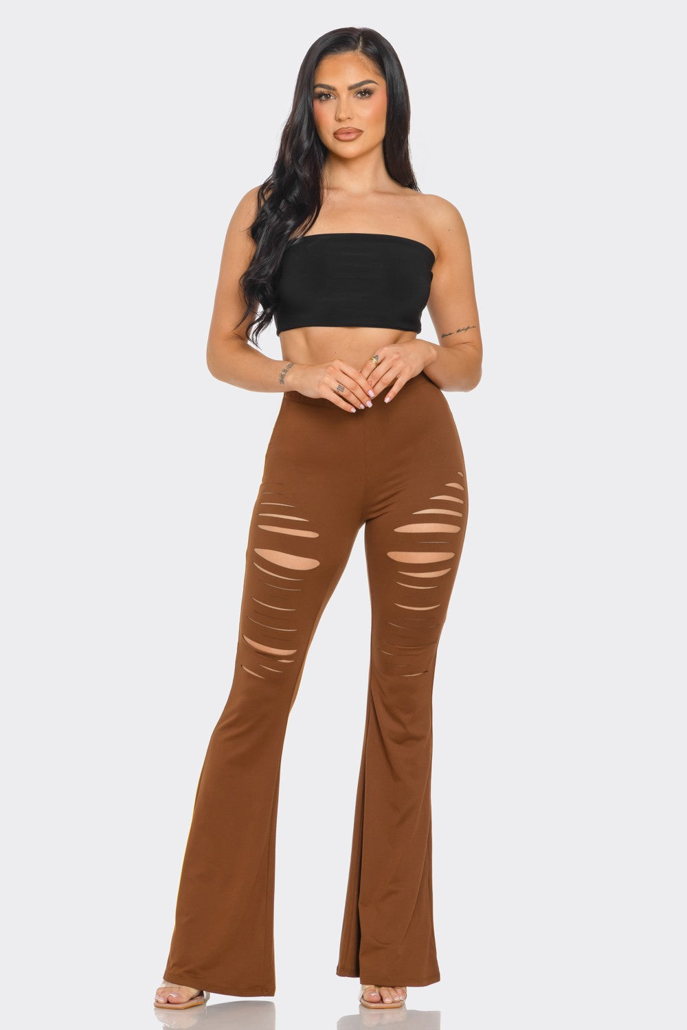 Woman wearing a black strapless top and brown flared pants on a white background