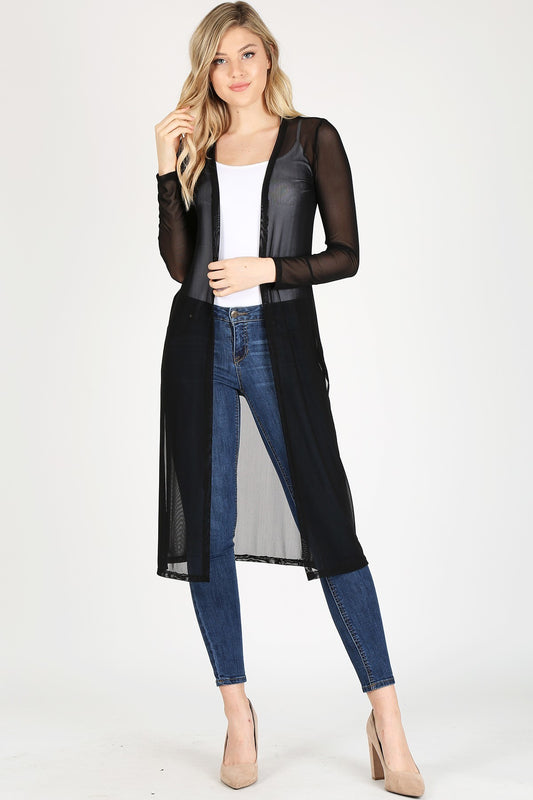Woman wearing a black sheer duster over a white top and blue jeans on a white background