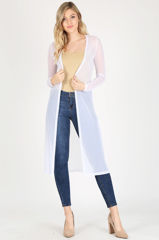 Woman wearing a sheer white cardigan over a beige top and blue jeans on a white background