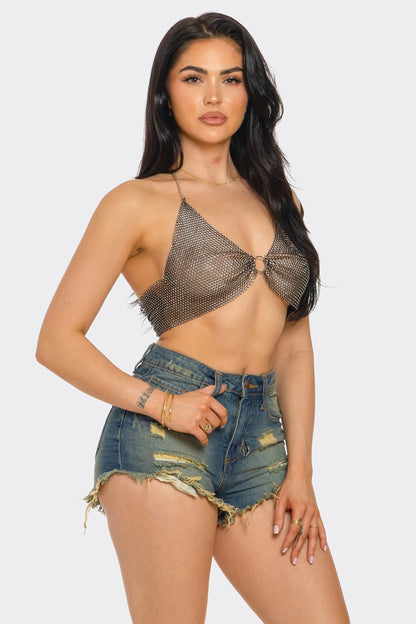 Woman wearing a chainmail top and denim shorts on a white background