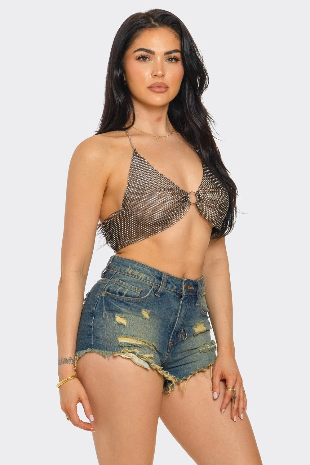 Woman wearing a chainmail top and denim shorts on a white background