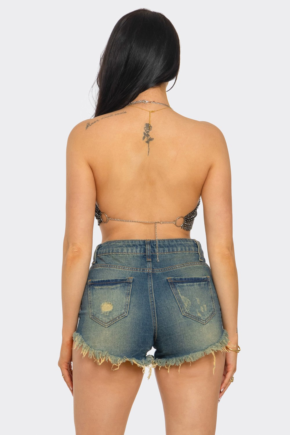 Person wearing a strapless top and denim shorts on a white background