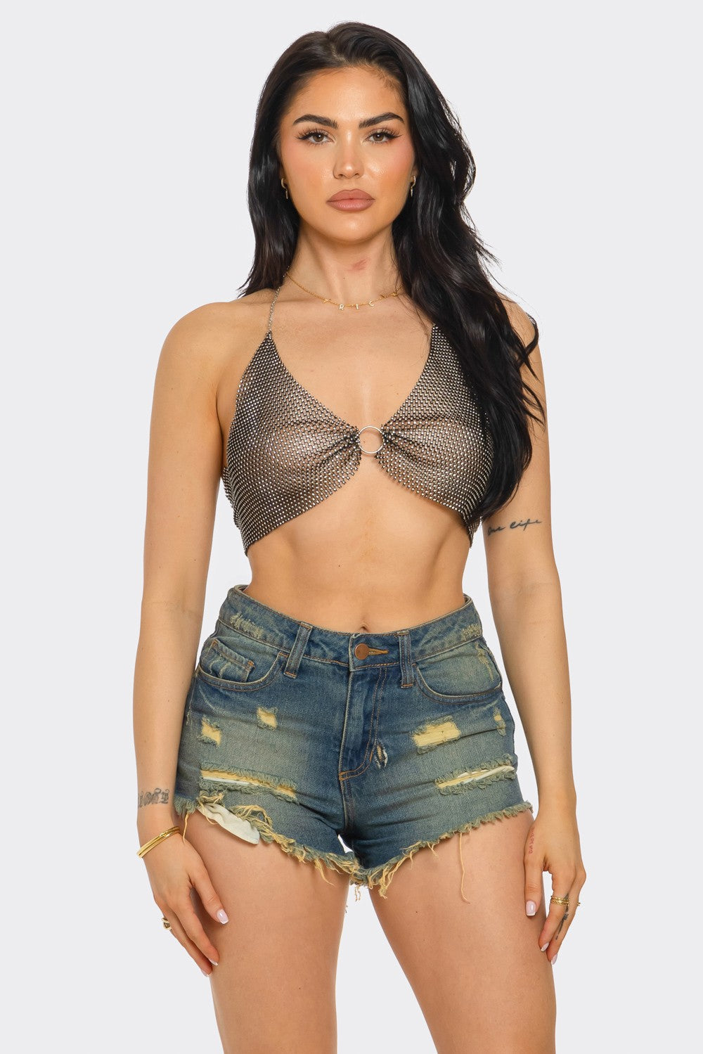 Woman wearing a chain top and denim shorts on a white background