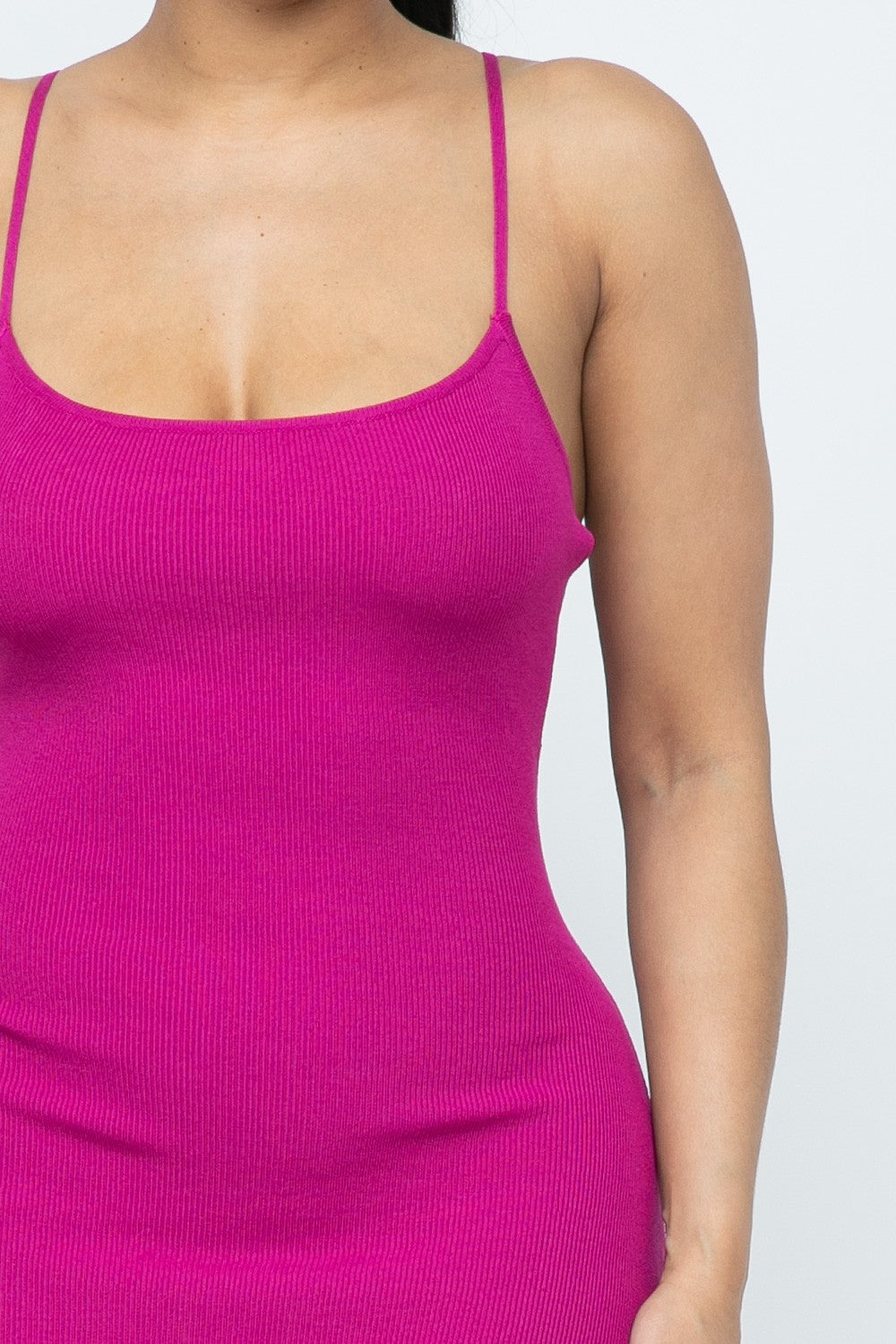 Close-up of a person wearing a magenta pink ribbed dress against a white background