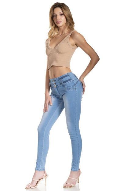 Woman wearing a beige top and light blue jeans on a white background