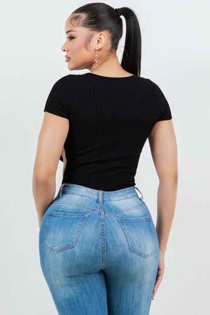 Woman wearing a black top and blue jeans against a white background