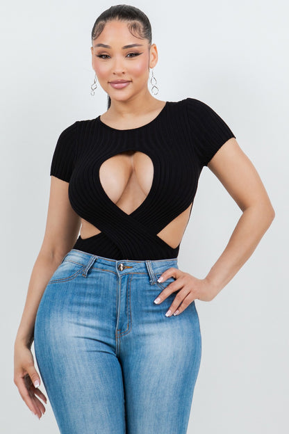 Woman wearing a black ribbed top with cut-out design and blue jeans on a white background