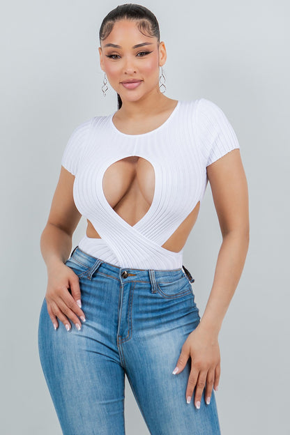 Woman wearing a white cut-out top and blue jeans on a gray background