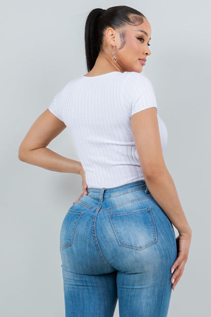 Woman wearing a white top and blue jeans against a gray background