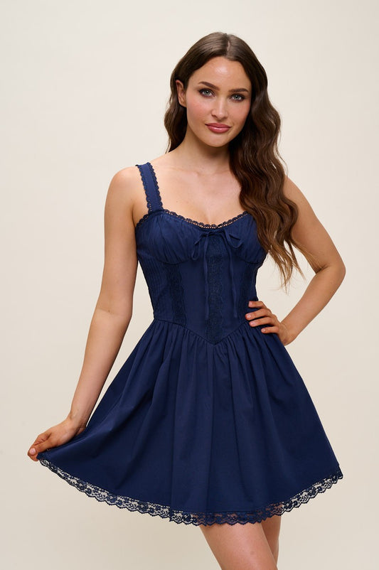 Woman wearing a navy blue dress with lace details on a beige background