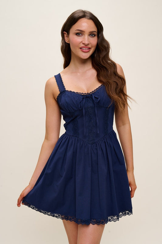 Woman wearing a navy blue dress with lace trim on a beige background