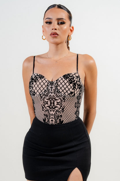 Woman wearing a black velvet bodysuit with a plain background