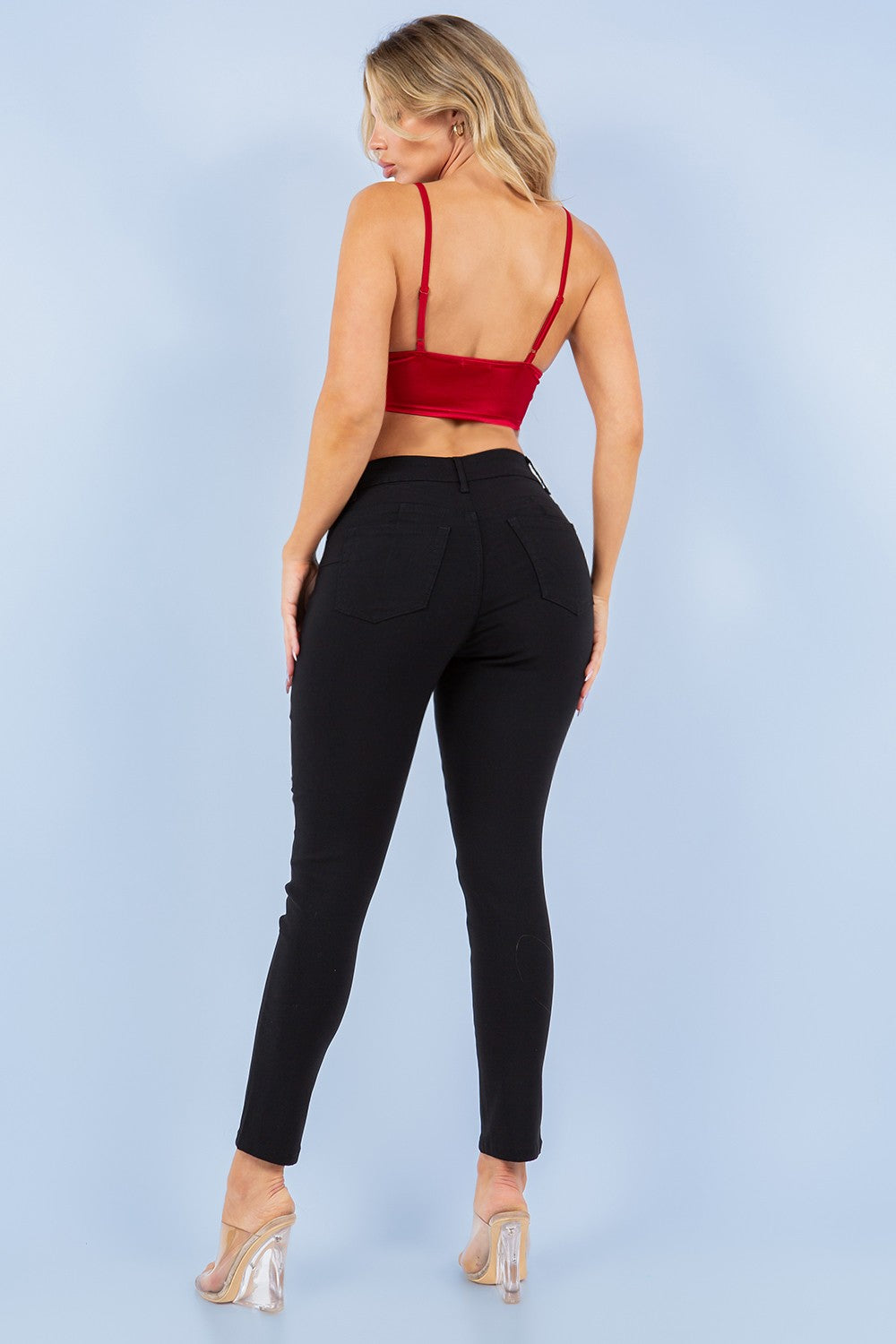 Woman wearing a red top and black pants against a light blue background
