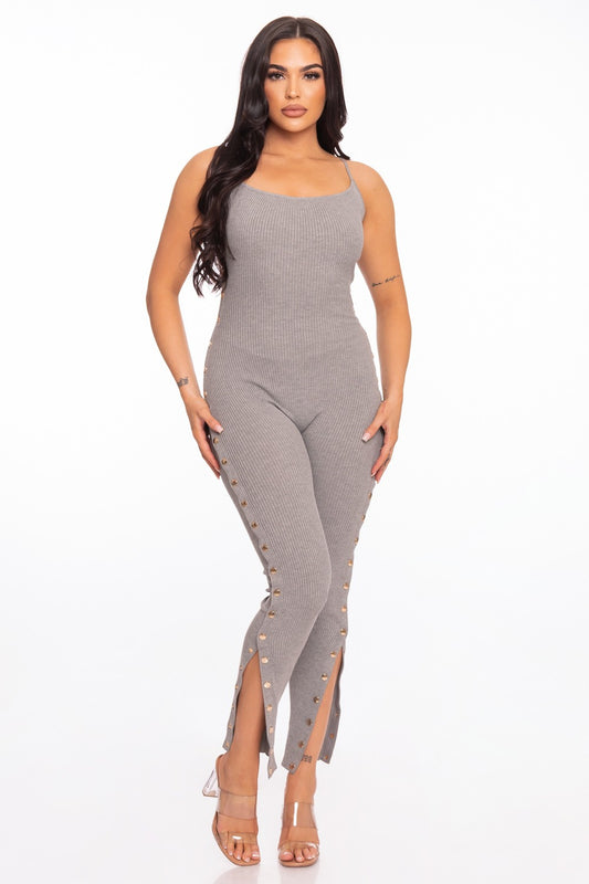 Woman wearing a heather grey sleeveless jumpsuit with a slit on a white background