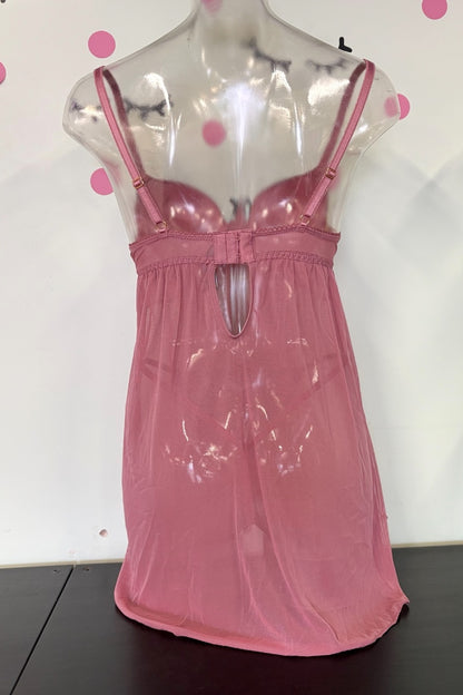 A pink sheer mesh slip dress with thin shoulder straps and a keyhole cutout at the bust, displayed on a clear mannequin torso against a white wall with pink polka dots.