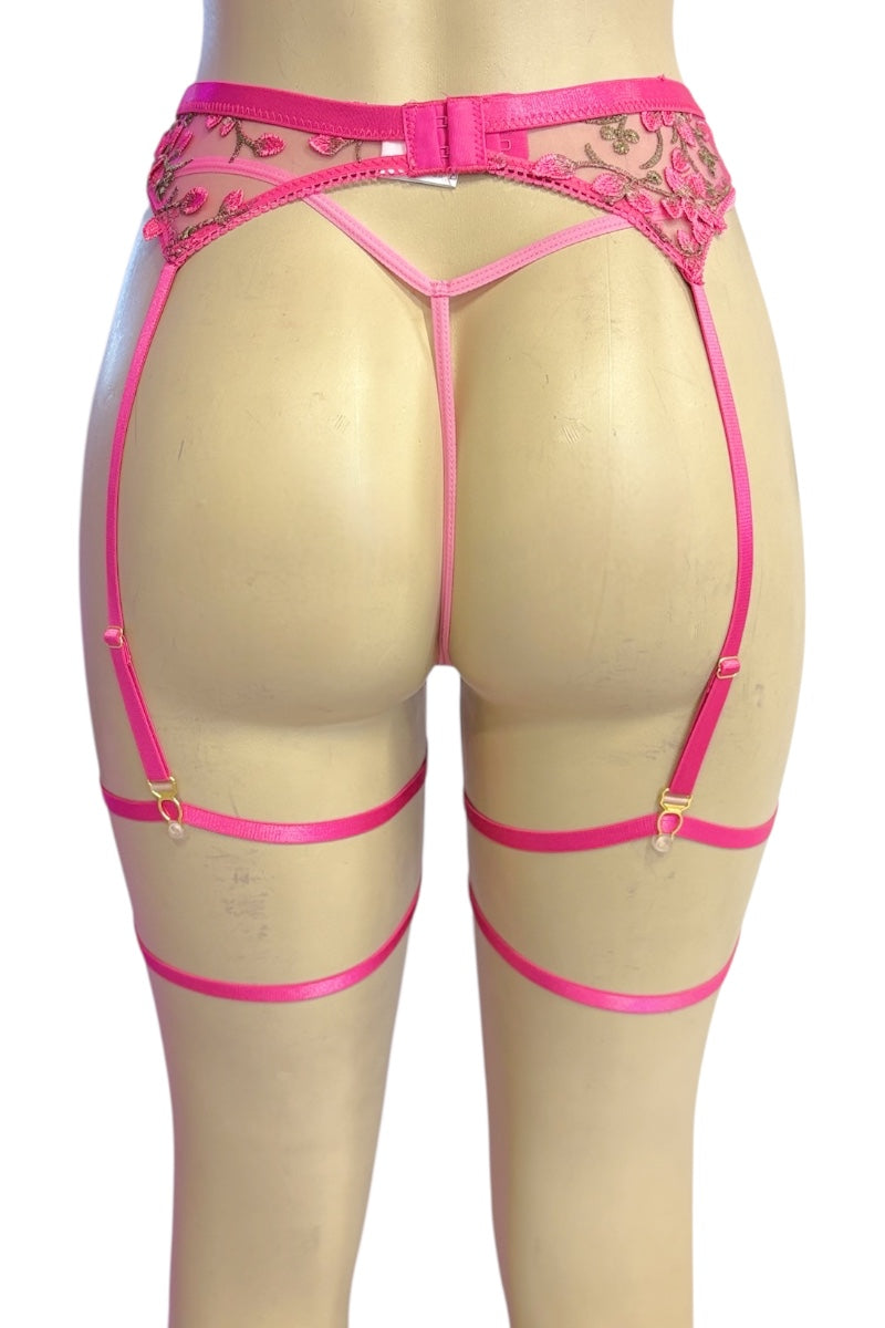 Bright pink lace and satin garter belt with leg straps, shown from the back on a beige mannequin against a white background.