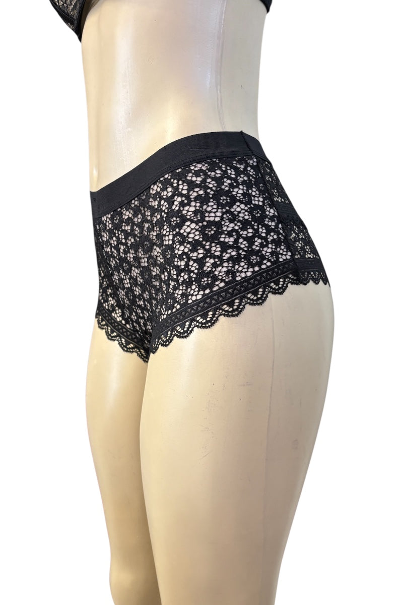 Black lace panties displayed on a beige mannequin torso against a plain white background.
