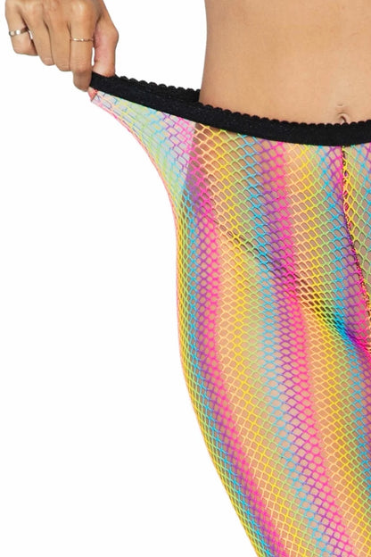 Close-up of a person wearing a bright rainbow-striped fishnet skirt or shorts, pulling the waistband slightly outward with a hand. The fabric has vertical stripes in pink, yellow, blue, and green with a black scalloped trim.