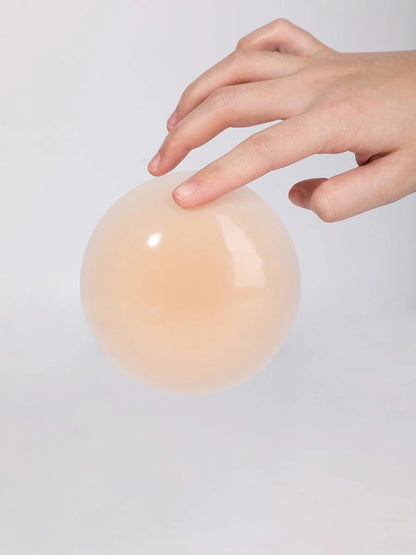 Hand touching a smooth, beige nipple cover on a light gray background