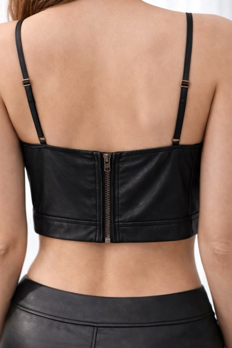 Black leather crop top with a zipper on a plain background