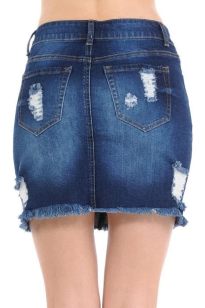 Ripped blue denim mini skirt with distressed details and frayed hem, shown on a model from the back.