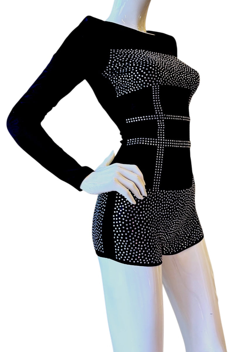 A black long-sleeve romper with silver rhinestone embellishments, displayed on a white mannequin against a white background.