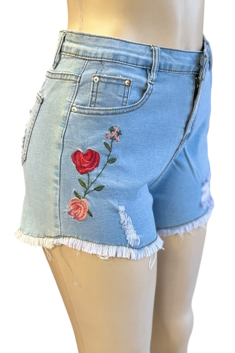 Denim shorts with floral embroidery on a mannequin against a white background