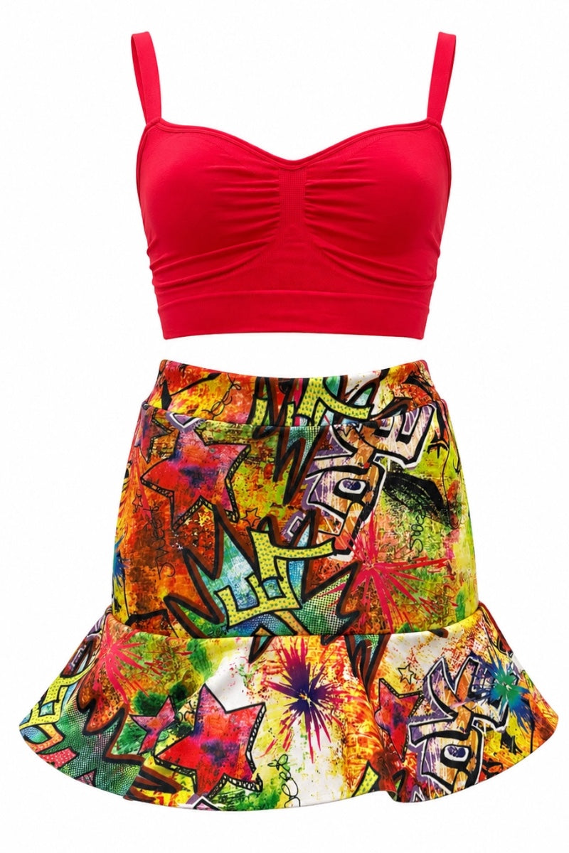 A two-piece set featuring a bright red ribbed scoop-neck bikini top with spaghetti straps and a high-waisted, flared skirt with a vibrant graffiti print in yellow, green, red, orange, and blue.
