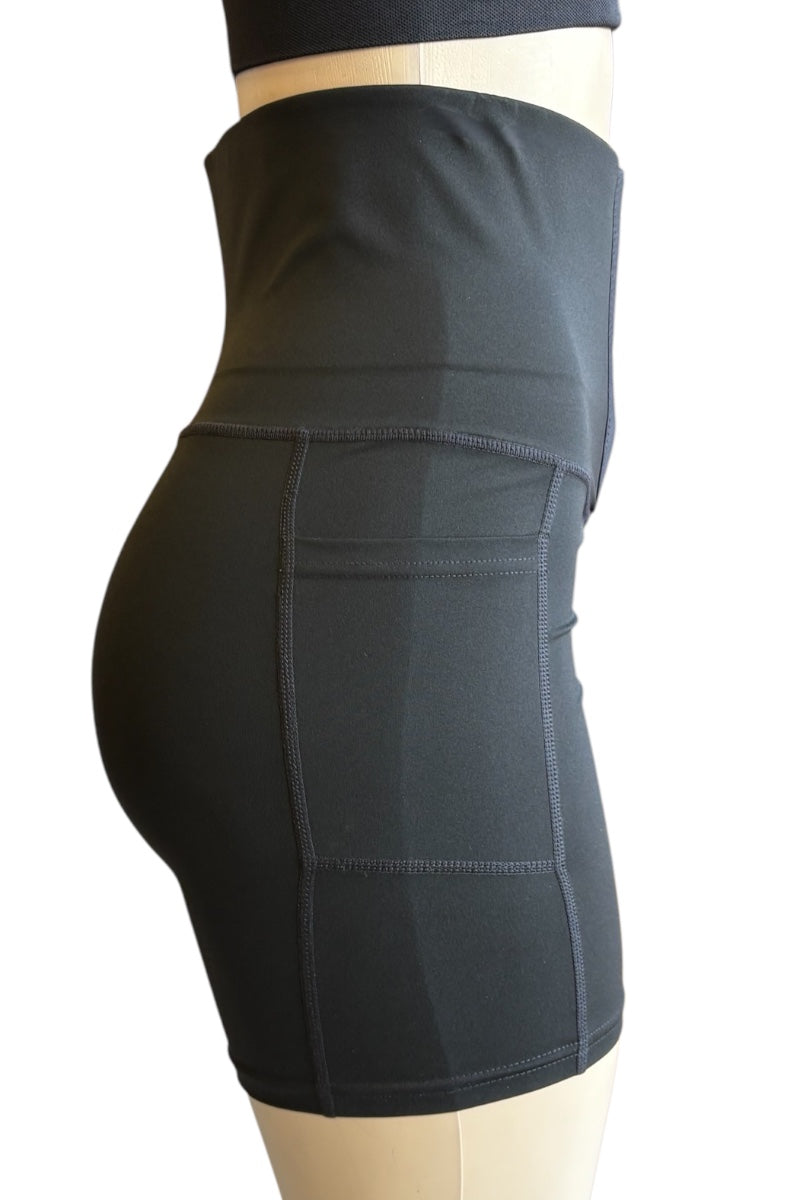 Black high-waisted compression shorts with side pockets, shown on a mannequin from a side profile view against a white background.