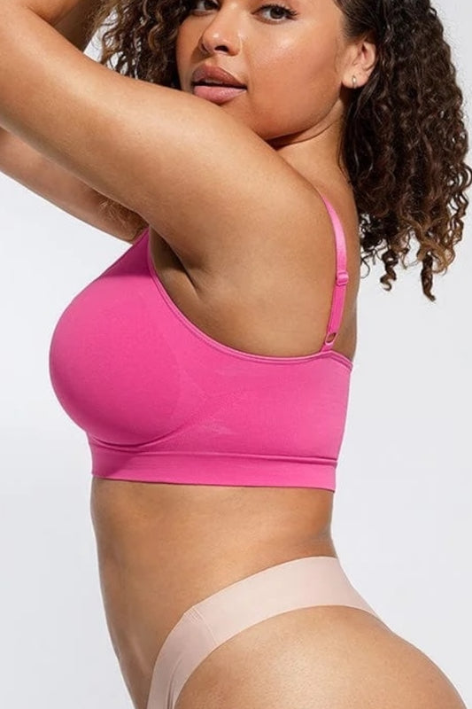 Woman wearing a fuchsia bralette and beige underwear on a white background