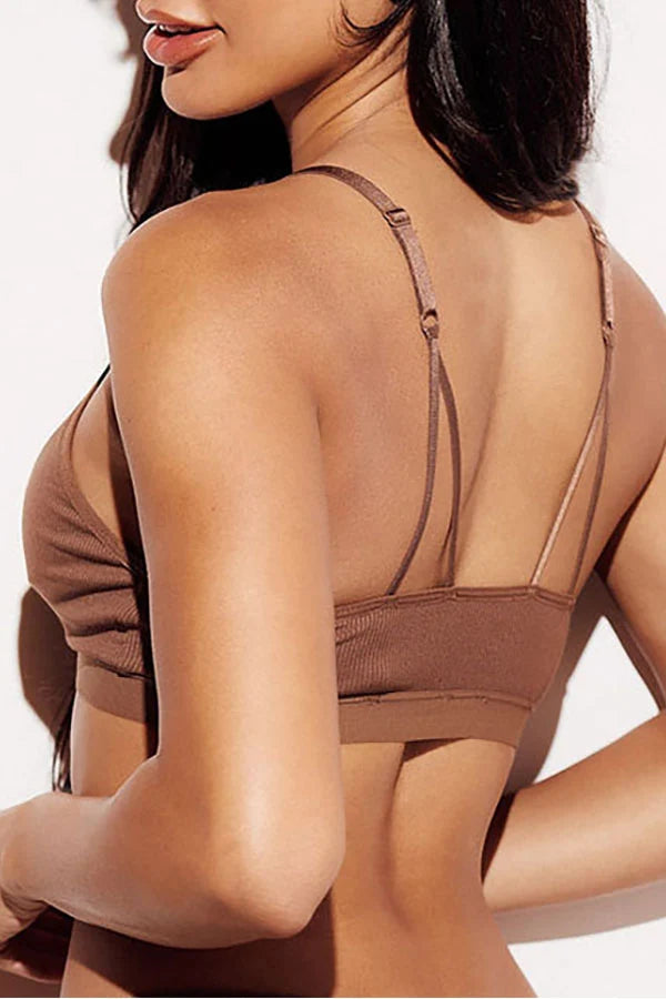 Close-up back view of a woman wearing a brown ribbed bralette with thin adjustable shoulder straps against a plain white background.