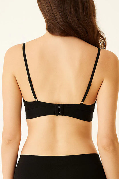 Black strappy top worn by a person on a beige background
