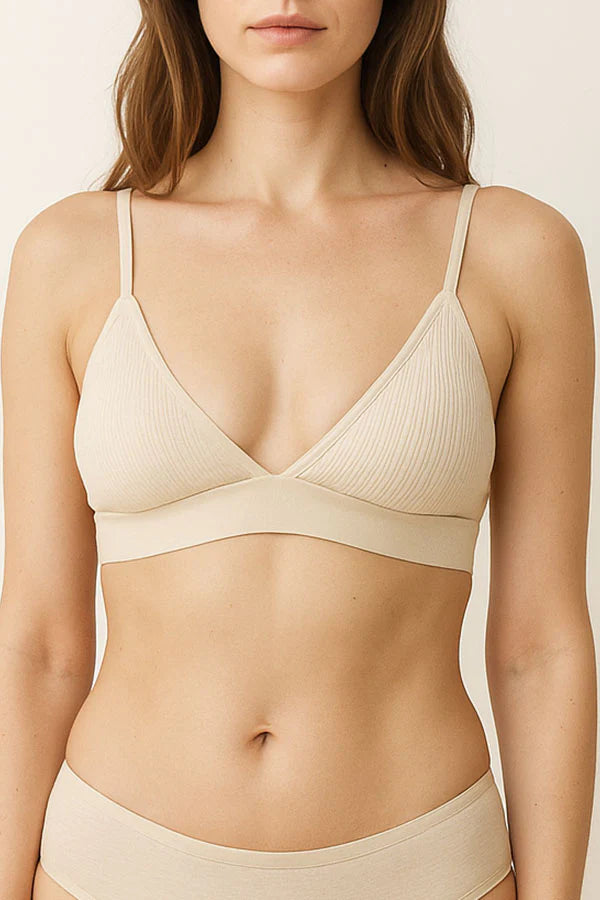 Woman wearing a cream bra and underwear set against a neutral background