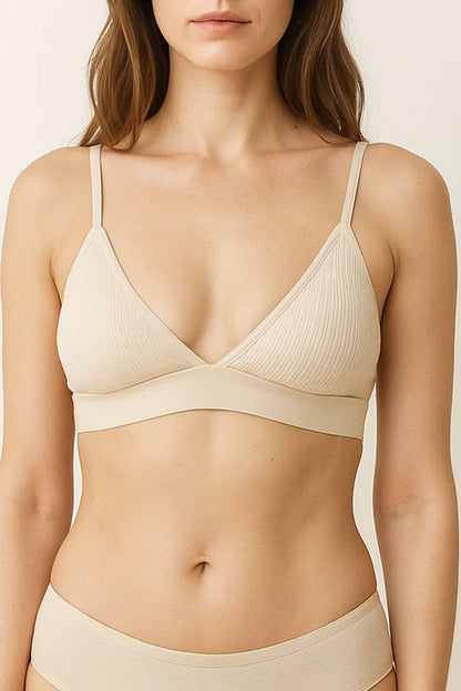 Woman wearing a cream bra and underwear set against a neutral background